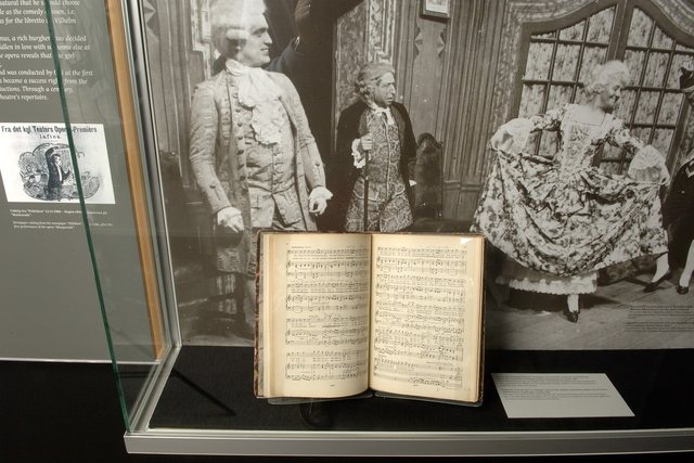 An open manuscript in a lit museum display case