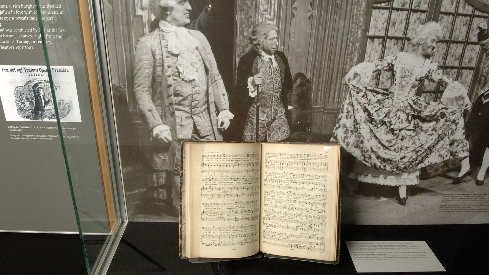 An open manuscript in a lit museum display case