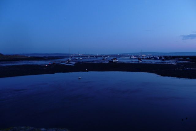 A small harbour at low tide in the blue light of dusk