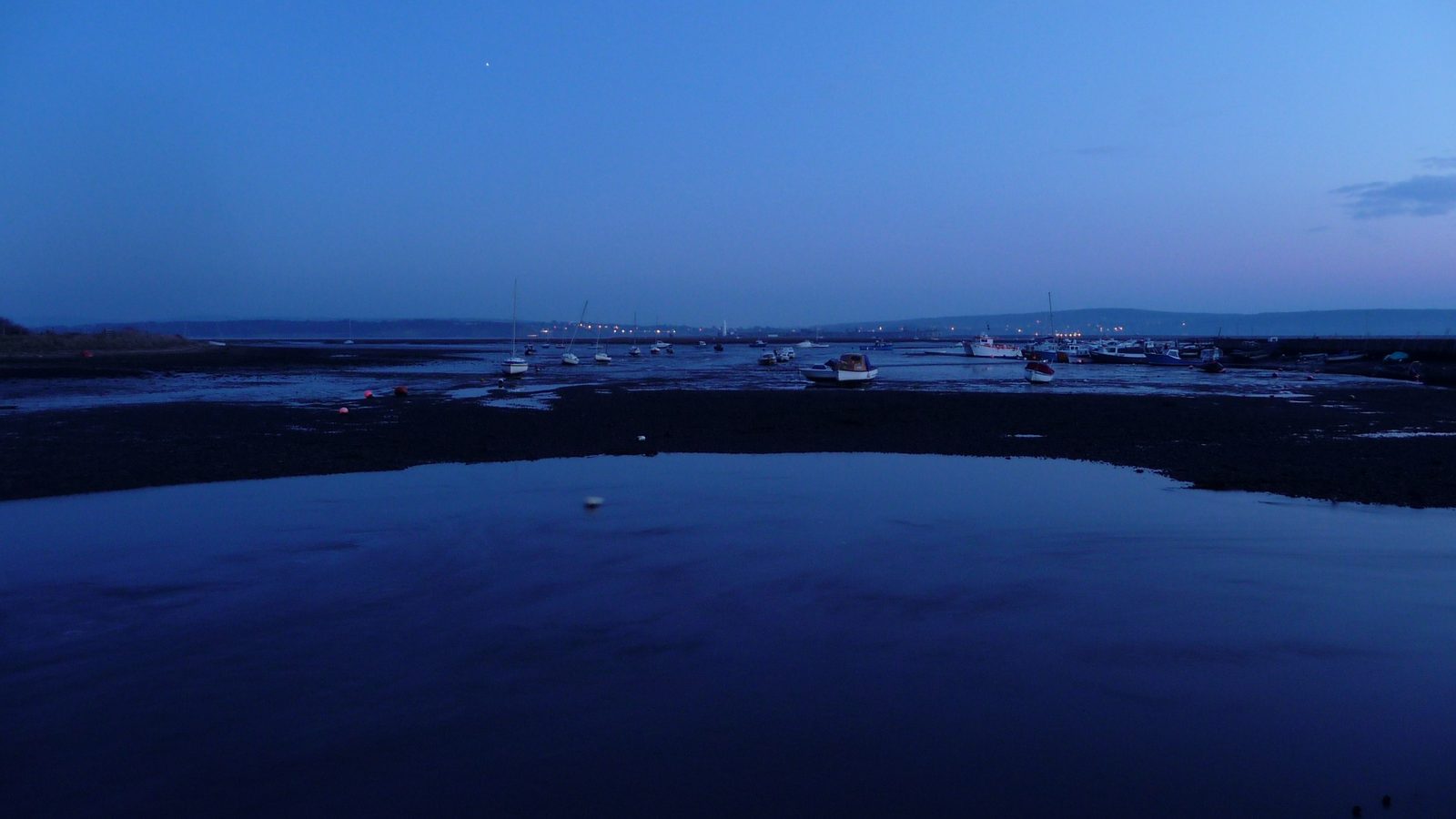 A small harbour at low tide in the blue light of dusk