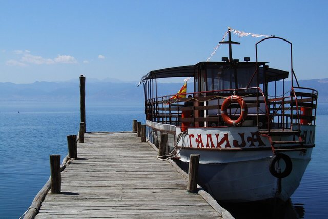 An old wooden boat moored at a wooden jetty on a wide lake