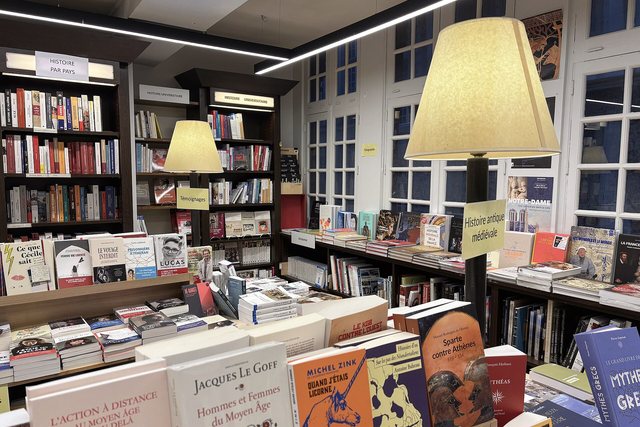 Tables of books beneath wide lampshades in a quiet bookshop