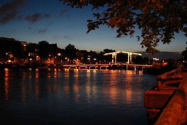 A lifting bridge outlined in lights across a canal at dusk