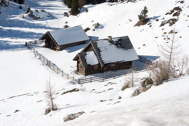 Log cabins under snow on an open mountain slope