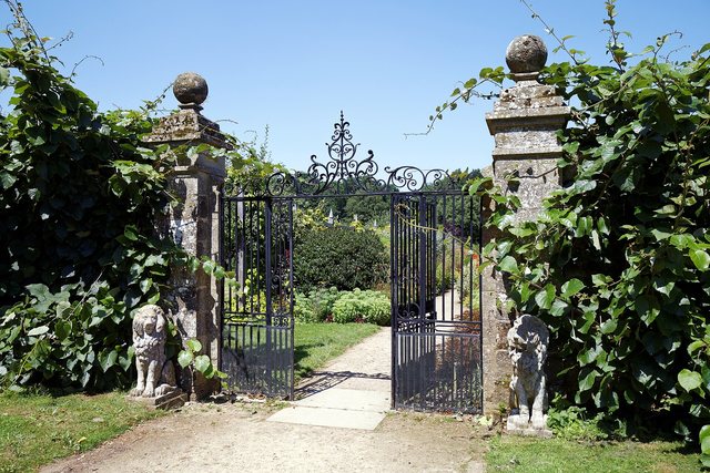 An open wrought-iron gate into a walled garden