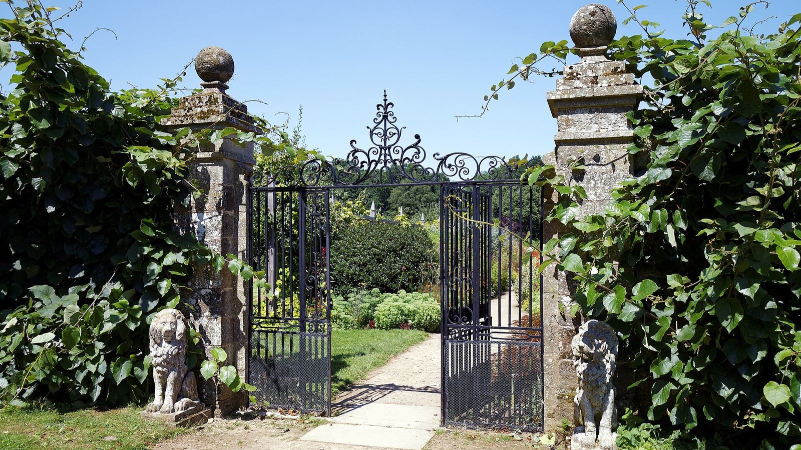 An open wrought-iron gate into a walled garden