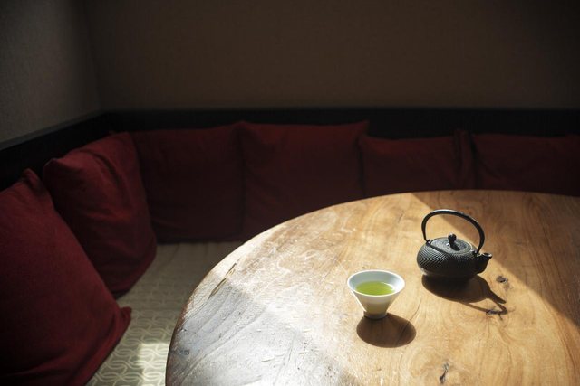 A cast-iron teapot and one small cup on a table in a dim tea room