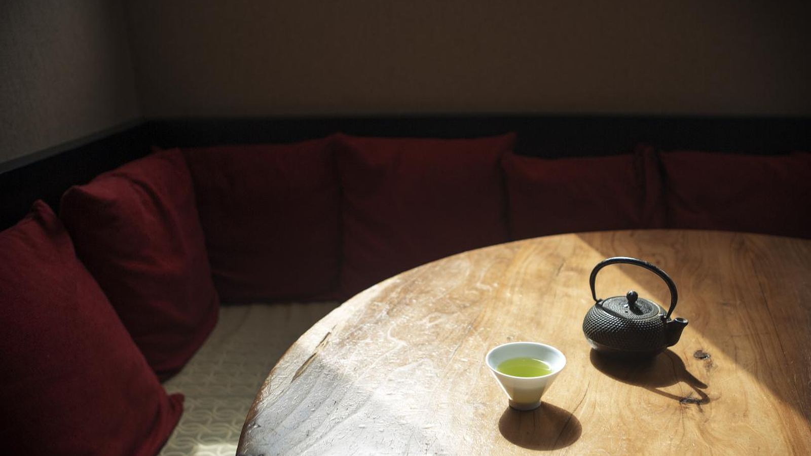 A cast-iron teapot and one small cup on a table in a dim tea room