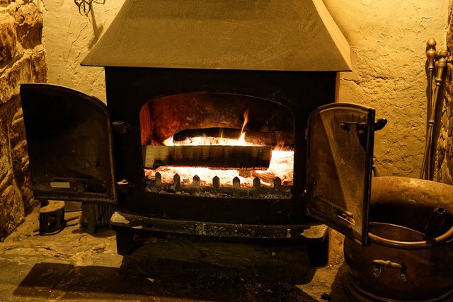 A wood-burning stove alight in a stone hearth