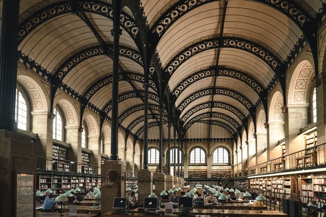 Green lamps along the long tables of a vaulted reading room