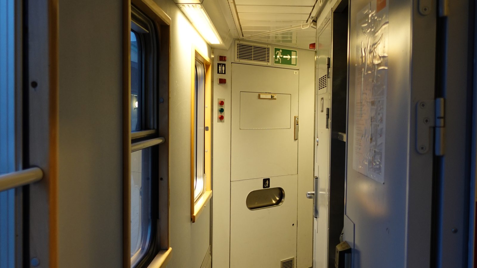 The dim corridor of a sleeping car at night, lit by one lamp