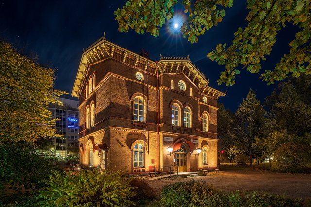 A small old railway station lit from within on a moonlit night