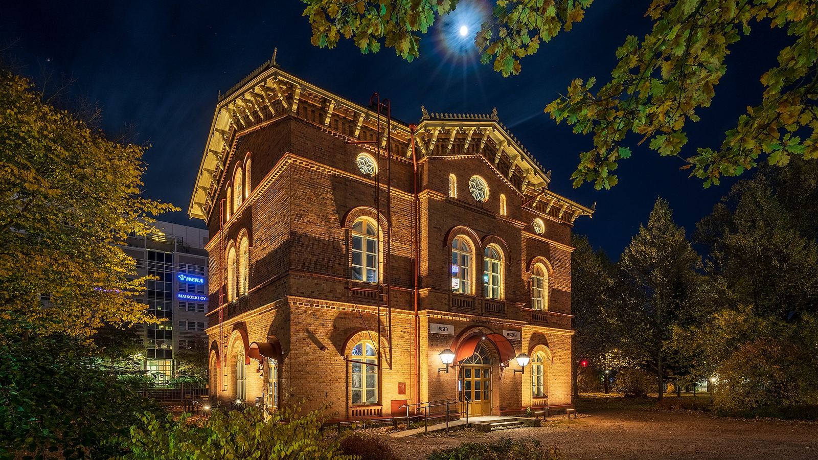A small old railway station lit from within on a moonlit night
