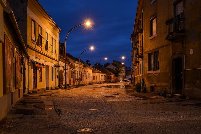 A cobbled village street at blue hour beneath a single lamp