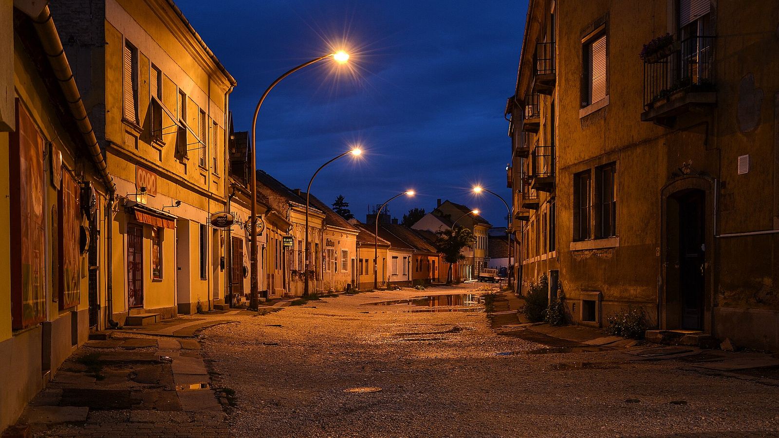 A cobbled village street at blue hour beneath a single lamp