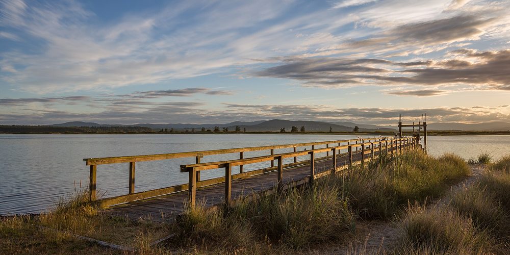 A wooden pier running out toward the water at dusk
