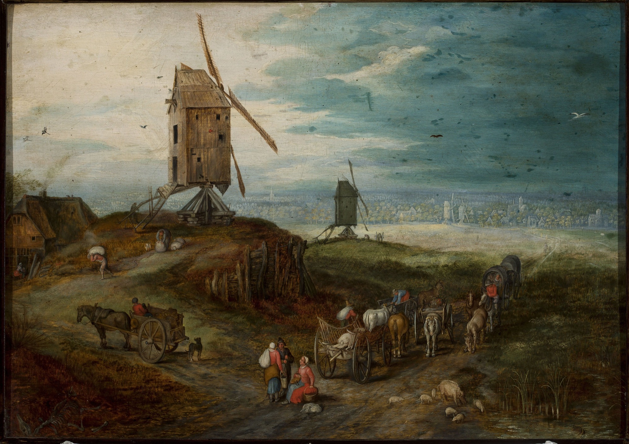 A Flemish country road with horse-drawn carts, walkers and pigs, a large wooden windmill on a hill and a wide plain with a distant town beyond.